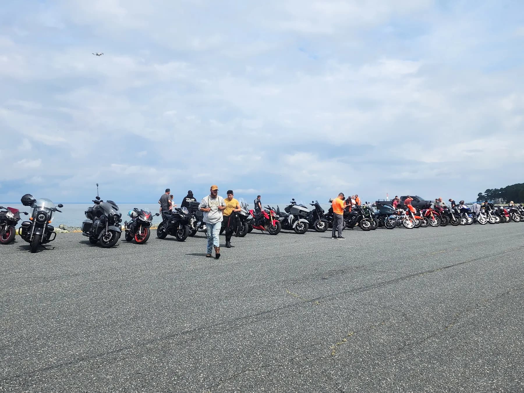 A long line of motorcycles at the water's edge